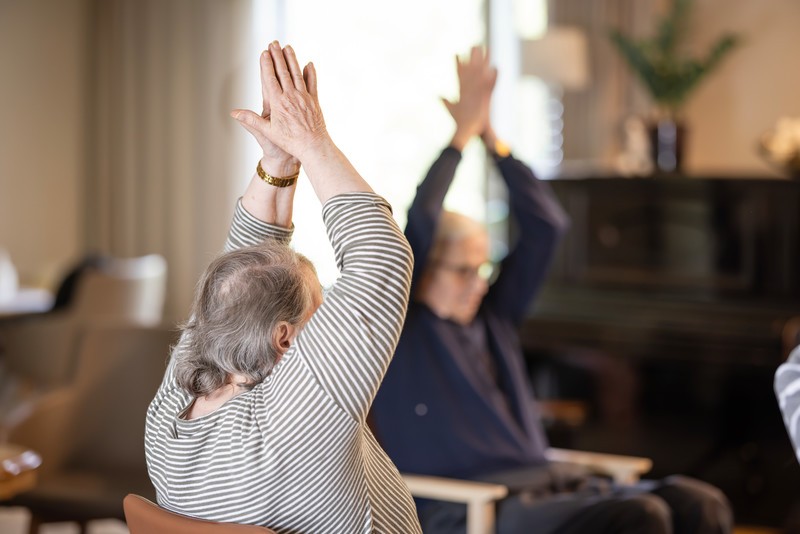 Iäkäs nainen osallistuu jumppaan hoivakodissa