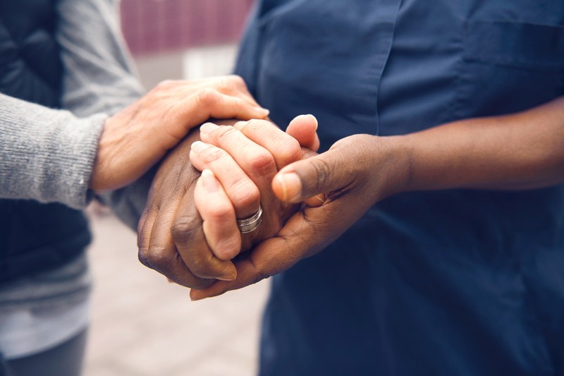 Kädet pitelemässä toisiaan ystävällisesti ulkona, symboloiden tukea ja huolenpitoa