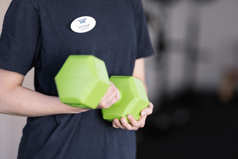 Henkilö pitää vihreitä käsipainoja