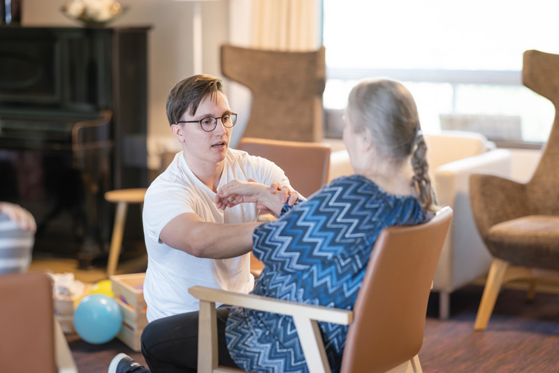 Fysioterapeutin kuntoutushetki ikäihmisen kanssa sisätiloissa