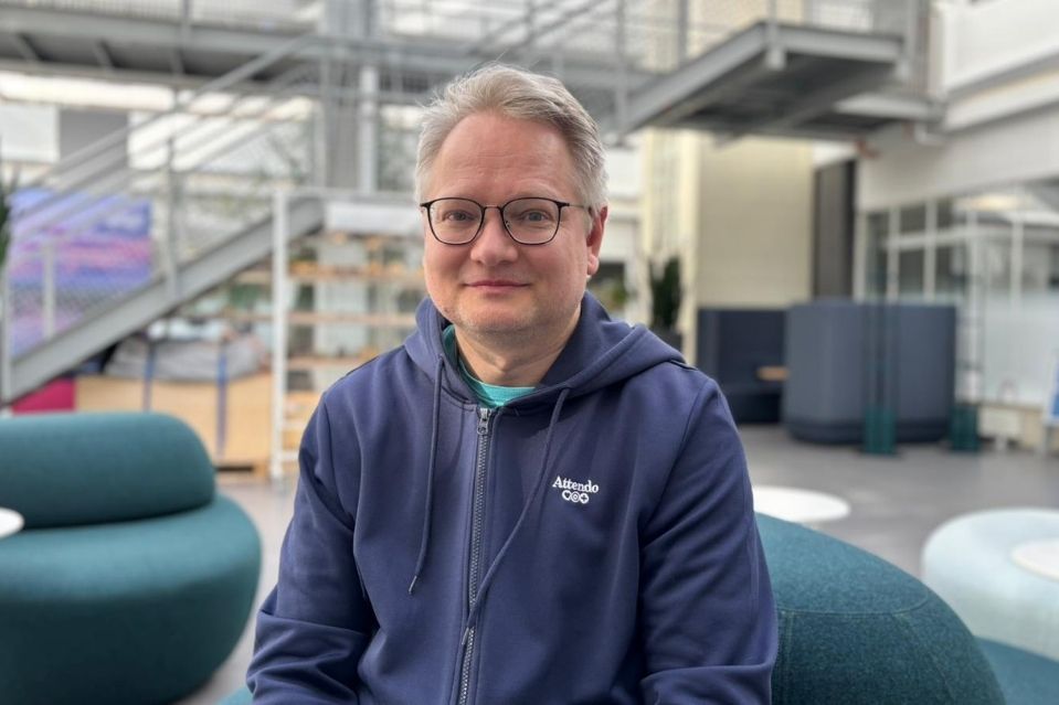 Lähihoitaja Kimmo hymyilee kameraan sininen huppari päällä.