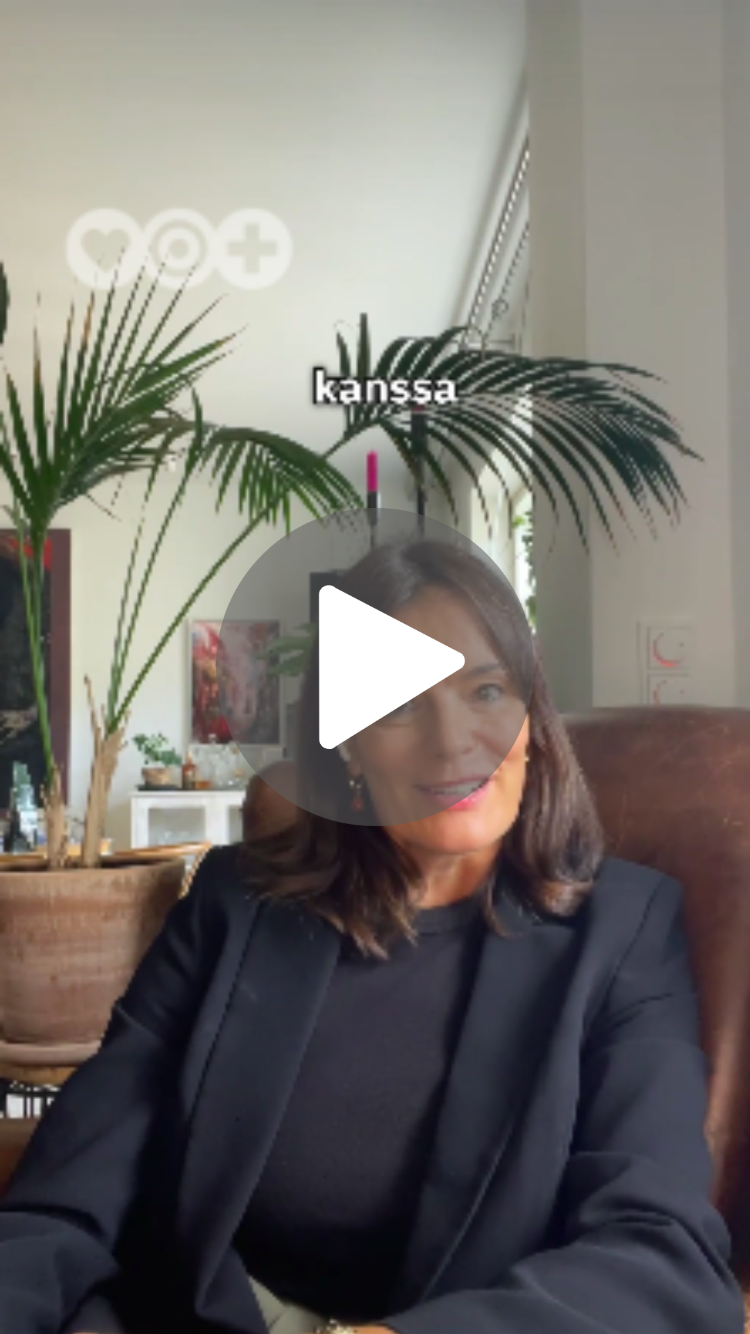 Nainen istuu nahkatuolissa sisätiloissa, taustalla iso viherkasvi ja ikkuna