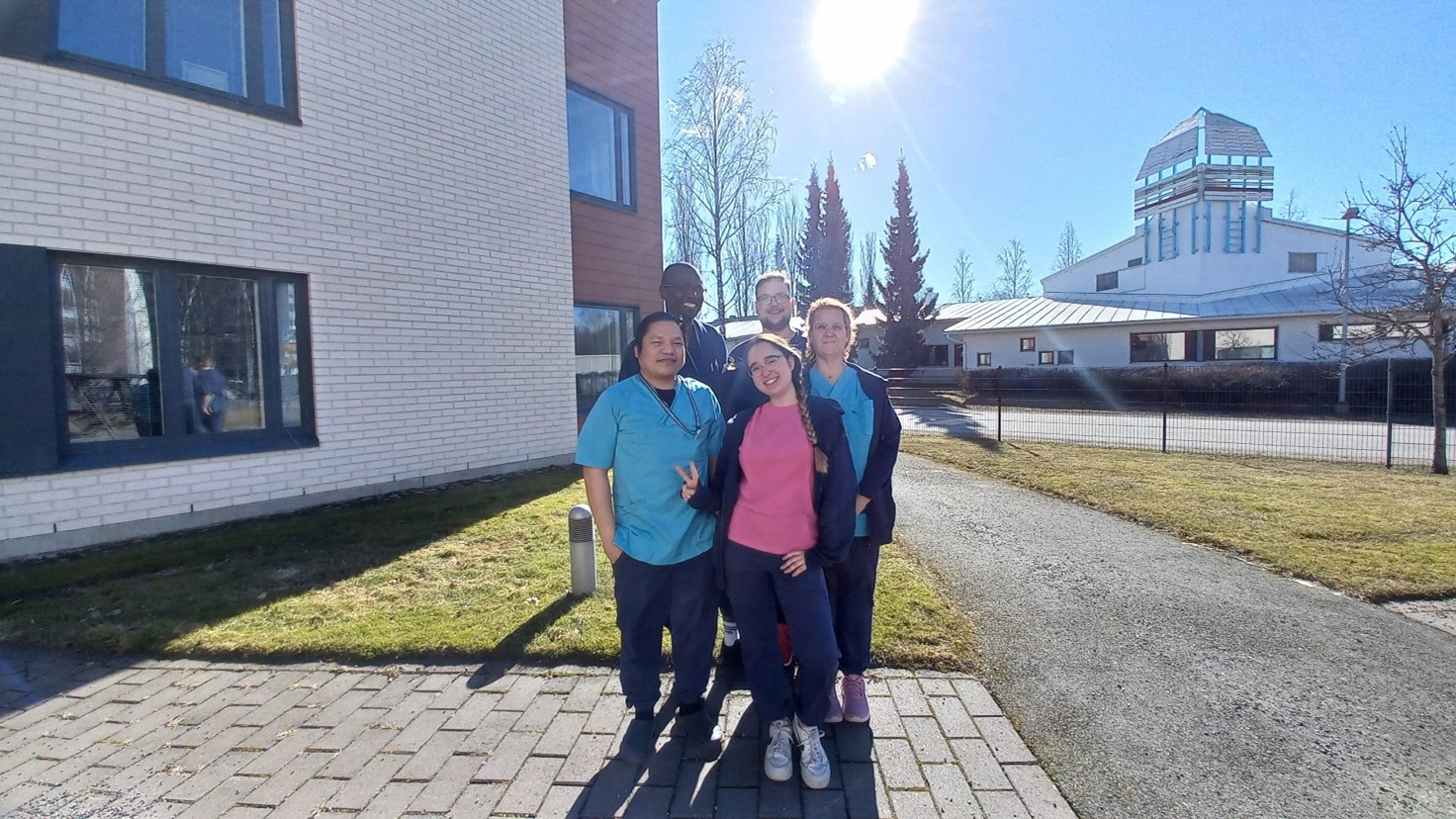 Erasmus-opiskelija Marta ja ohjaajat Marlon, Tafa ja Eino sekä tiimiesihenkilö Minna hymyilevät yhdessä Attendo Retonkihovissa.