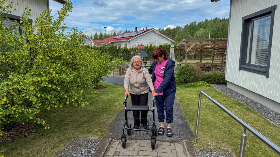 Sairaanhoitaja Noora Oksanen ja hoivakodin asukas k&auml;velev&auml;t yhdess&auml; ulkona Attendo Katarinanpuistossa.