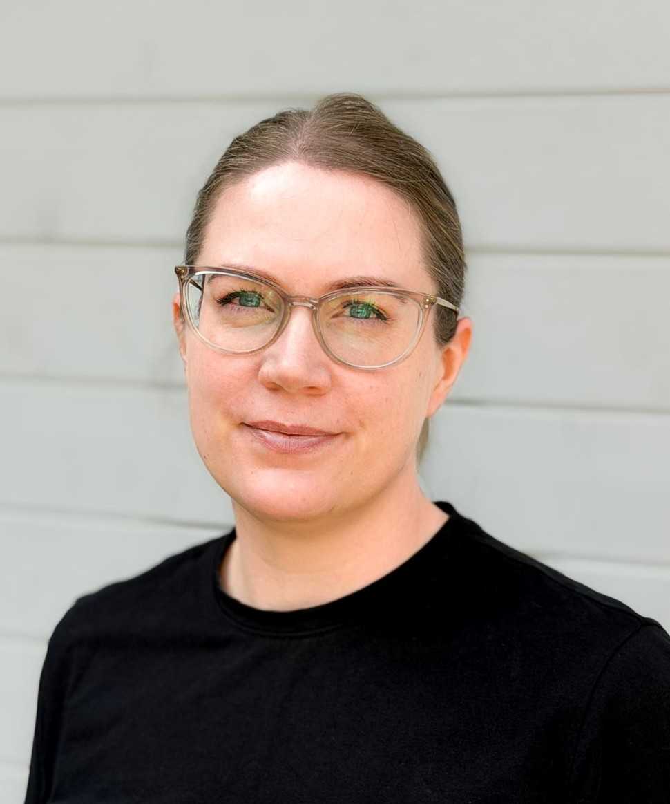 Riina katsoo suoraan kameraan, musta pusero päällä