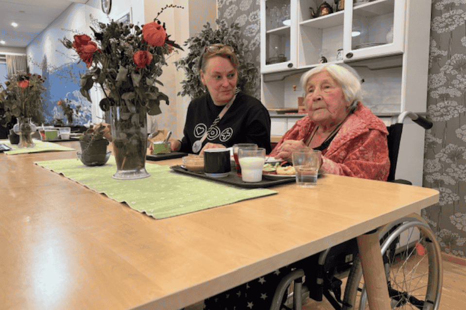 Hoivakodin johtaja Katri pöydän ääressä aamupalalla asukkaan kanssa 