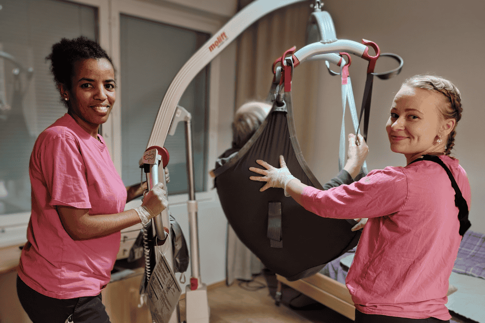 Kaksi hoitajaa k&auml;ytt&auml;&auml; nostotuolia yhdess&auml; hoivakodissa