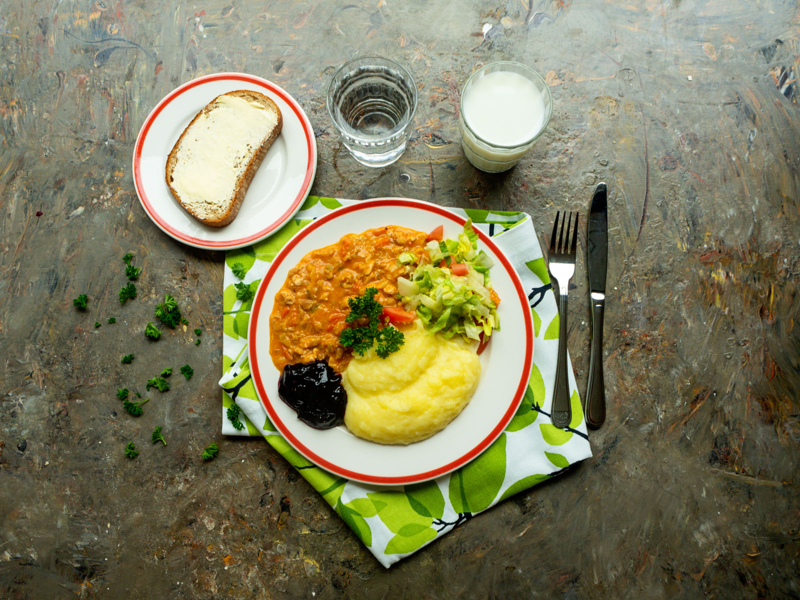 Lounas katettuna lautaselle, kastiketta, muusia ja salaattia sekä leipä ja maitolasi ja vesilasi