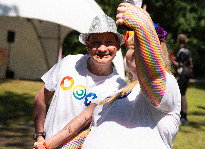 ohjaaja ja palvelukodin asukas pride-tapahtumassa, ohjaaja ottaa kuvaa puhelimella